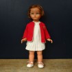 Vintage doll with white pleated dress and red cardigan
